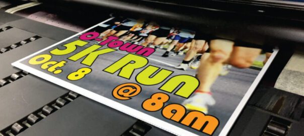 A poster for a 5k run is printed on a printer.