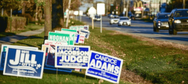 A row of political signs on the side of the road.